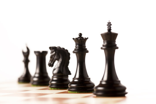 Black chess pieces on a chessboard standing in perspective