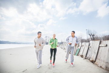 Group of young athletes jogging on the beach
