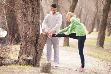 Obraz premium Young woman doing relaxation exercise with young man helping her