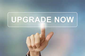 business hand clicking upgrade now button on blurred background - 80682459