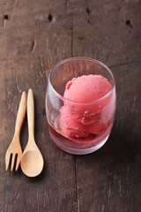 red homemade ice cream scoops in a clear glass on wooden backgro