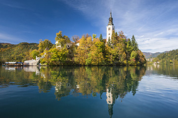 Fototapeta na wymiar beflry and church in reflections on lake in Slovenia