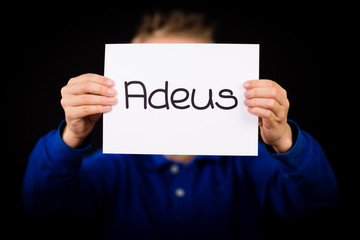 Child holding sign with Portuguese word Adeus - Goodbye