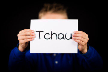 Child holding sign with Portuguese word Tchau - See You Later