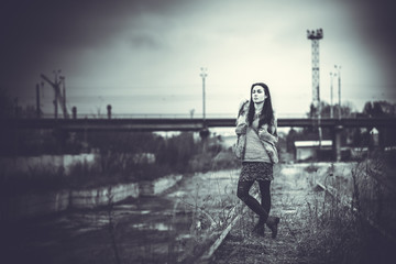 Long hair brunette girl outdoor with old industrial bridge behin