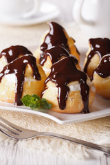 profiteroles with cream and chocolate glaze on a plate. vertical