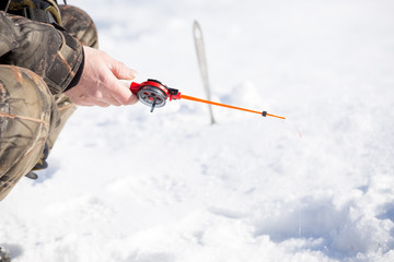 small rod for ice fishing in  hands near  hole