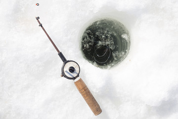 Hole with water and small rod for winter fishing