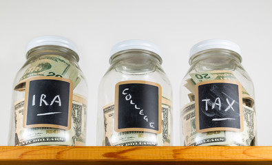 Three glass jars on wooden shelf for savings