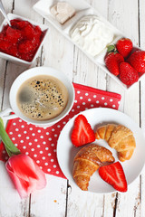 breakfast with croissants, strawberry  and cup of coffee on whit