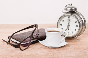 Glasses, notebook, alarm clock and  coffee cup
