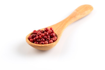 red peppercorns in wooden spoon isolated