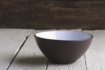 Brown and white salad bowl on white boards.