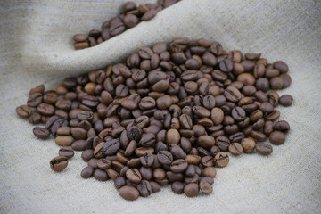 Heap of roasted coffee beans on sackcloth background