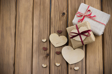 Fototapeta premium Gift boxes with red ribbon, wooden hearts on wooden background