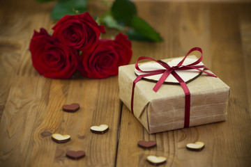 Red roses and gift box tied red ribbon with small wooden hearts