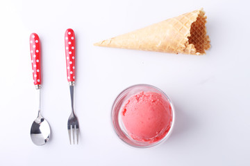 red homemade ice cream scoops in a clear glass with spoon and fo