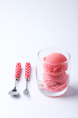 red homemade ice cream scoops in a clear glass with spoon and fo