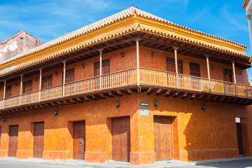 Obraz premium Hermosas calles y fachadas de las casas coloniales de la ciudad amurallada de Cartagena de Indias en Colombia. Casa de esquina color naranja