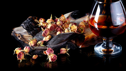 Red rose petals on books and bottle of wine.