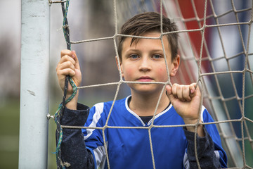 Little boy in goalkeeper uniform football goal on the stadium. © De Visu