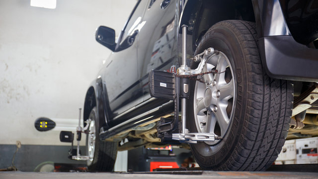 Car on stand with sensors on wheels for wheels alignment camber