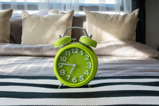 green alarm clock on bed in modern bedroom
