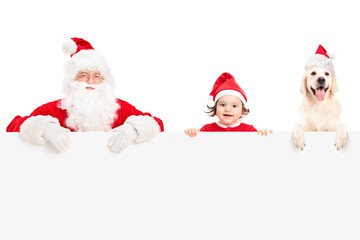 Santa, a baby girl and a dog posing behind panel