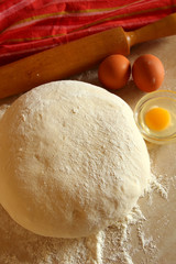 Yeast dough, eggs, and flour on the table, top view.