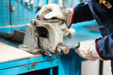 Worker securing a metal plate in a vise