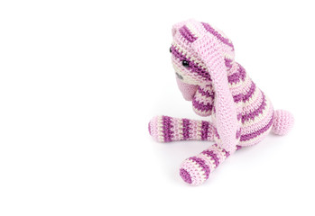 Knitted rabbit toy sitting isolated on white