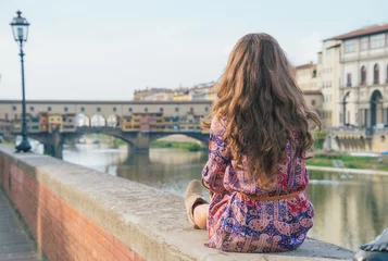 Photo sur Plexiglas Ponte Vecchio Young woman sitting near ponte vecchio in florence, italy.
