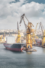 Fototapeta premium Cargo ship with crane in the harbor, Valletta, Malta
