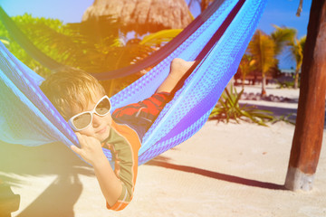 Fototapeta na wymiar happy little boy relaxed in hammock on the beach
