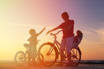Obraz premium father with two kids on bikes at sunset