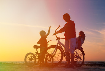 Fototapeta na wymiar father with two kids on bikes at sunset
