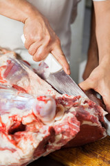 Obraz na płótnie Canvas Cropped Image Of Butcher Cutting Meat