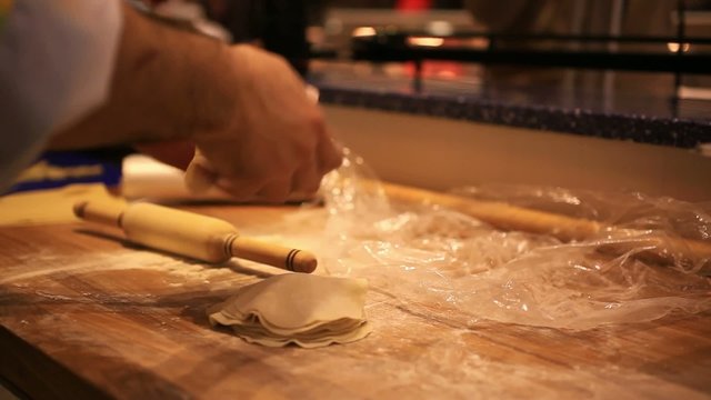 male chef hands preparing dough with rolling pin for asian food
