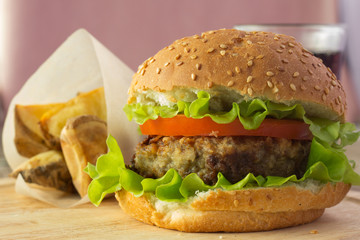 Burger on wooden plate and roasted potato wedges