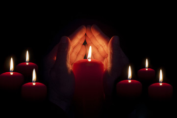 two hands illuminated by  a candle in the darkness