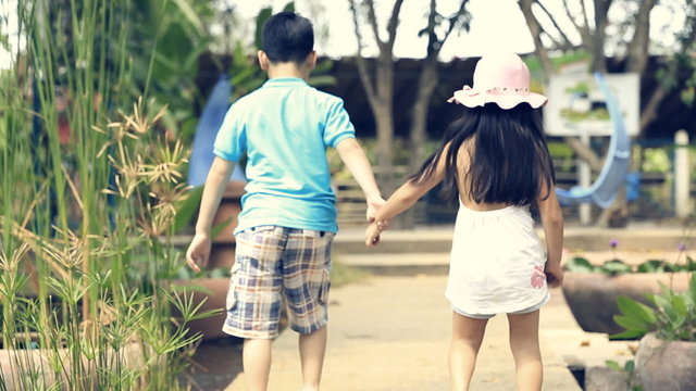 happy asian brother and sister walking in garden and laughing