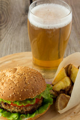 Burger, roasted potato wedges  and glass of beer