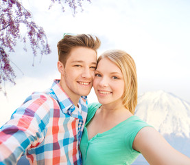 Fototapeta premium smiling couple with smartphone in city