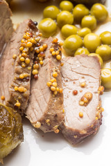 Roast beef cut in slices with peas on white dish