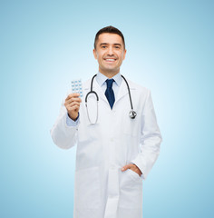 smiling male doctor in white coat with tablets