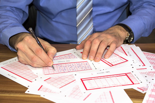 Young businessman Marking on lottery ticket with a pen