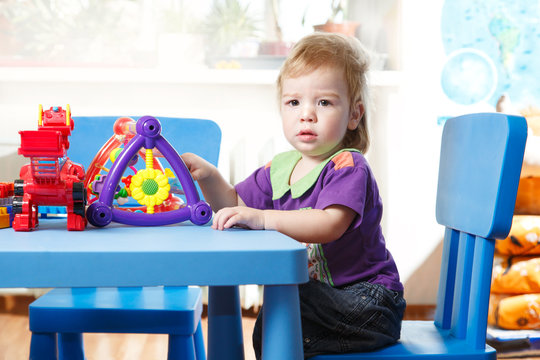 Toddler sitting at a table playing in home interior