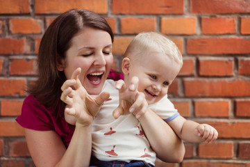 Mother and son making funny faces on a brick wall background