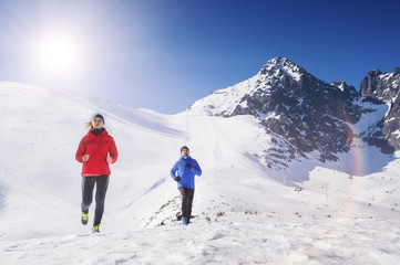 Fototapeta na wymiar Young couple jogging outside in sunny winter mountains
