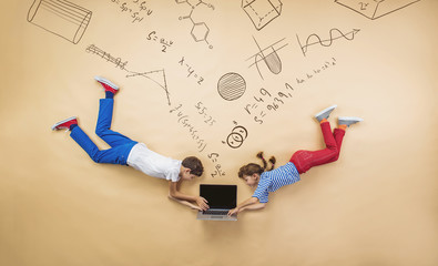 Cute boy and girl learning playfully in frot of a big blackboard © Halfpoint